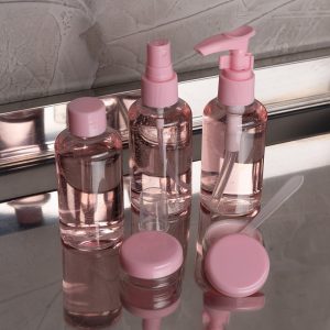 Kit de três garrafas pequenas na cor rosa transparente e as tampas na cor rosa sólida para produtos de higiene pessoal e dois potes menores na cor rosa para armazenar maquiagens.